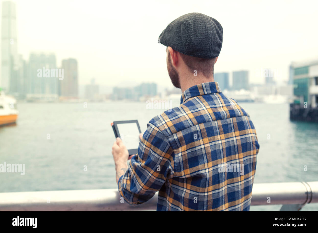 Mann mit digitalen Tablette weg an der Aussicht auf den Hafen suchen, Ansicht von hinten, Hongkong, China, Ostasien Stockfoto