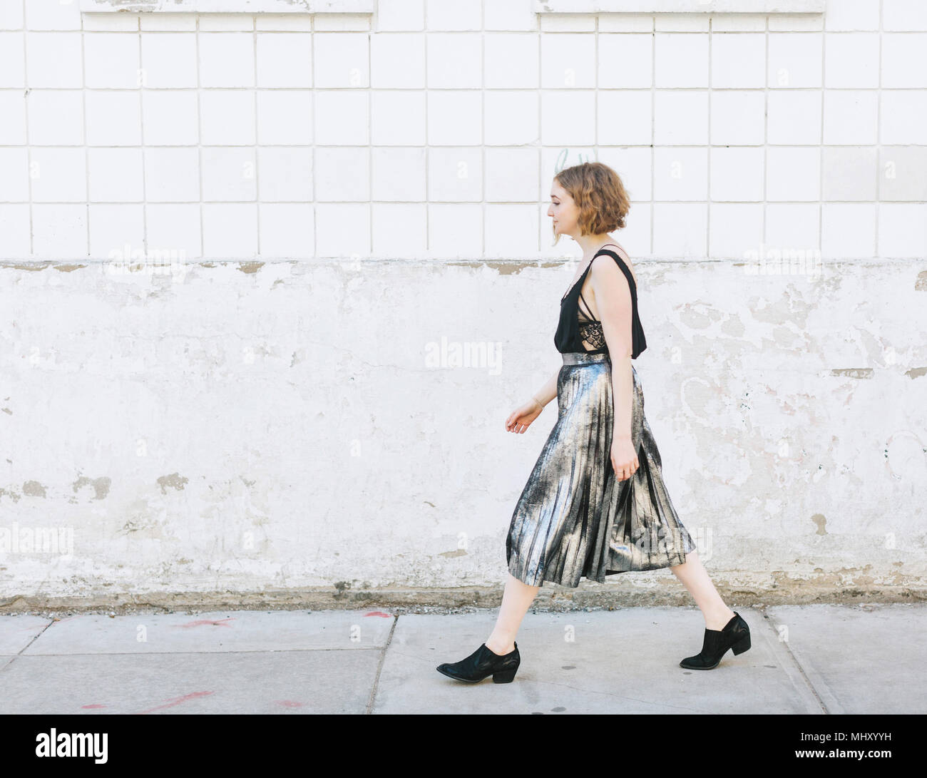 Frau in metallischen Rock Wandern in Street, volle Länge, Seitenansicht Stockfoto