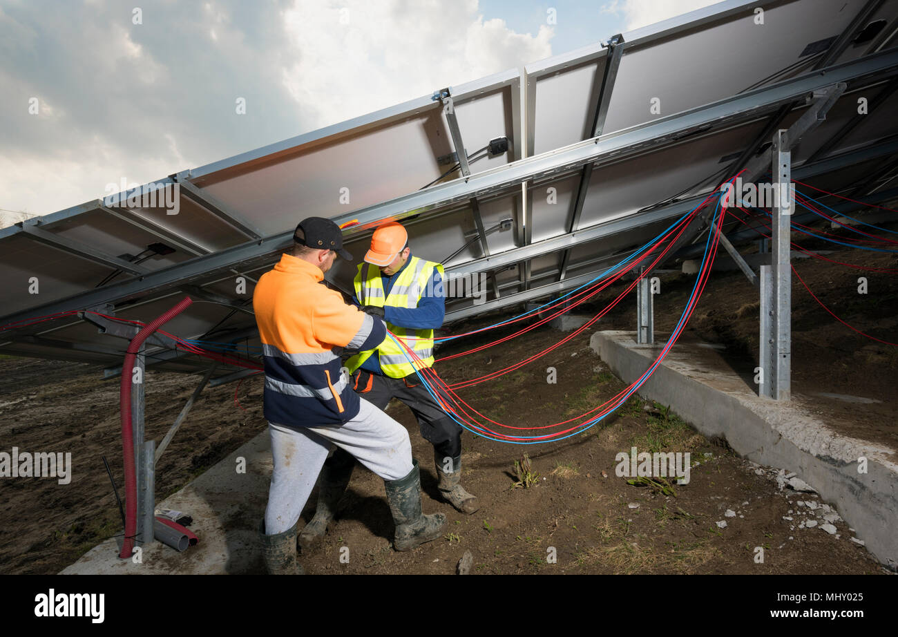 Ingenieure Connecting Solar Panels auf neue Solar Farm, auf der ehemaligen Deponie gelegen Stockfoto