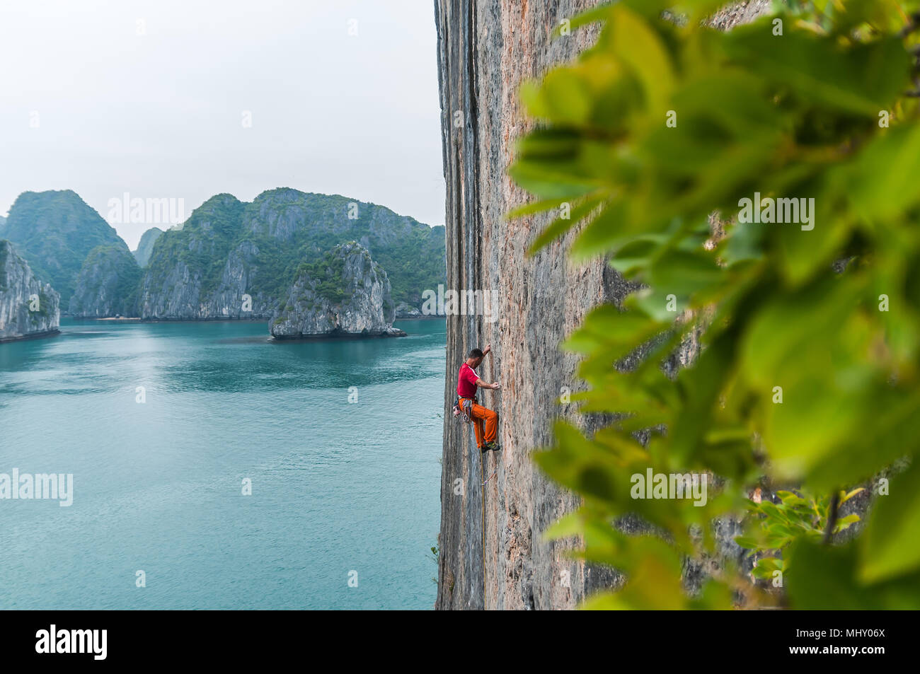 Man Klettern auf Kalkfelsen, Ha Long Bay, Vietnam Stockfoto