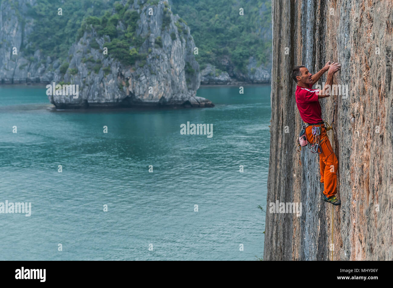 Man Klettern auf Kalkfelsen, Ha Long Bay, Vietnam Stockfoto