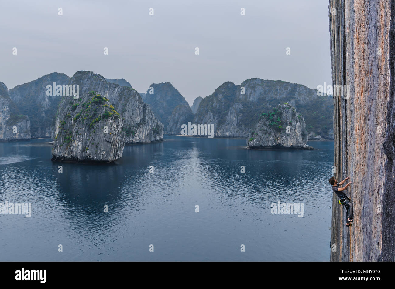 Man Klettern auf Kalkfelsen, Ha Long Bay, Vietnam Stockfoto