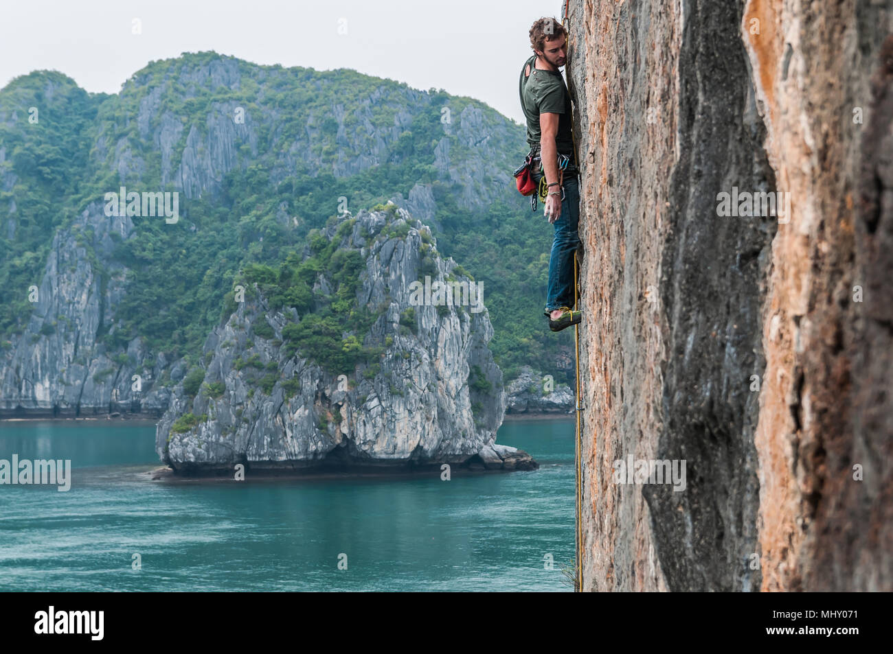 Man Klettern auf Kalkfelsen, Ha Long Bay, Vietnam Stockfoto