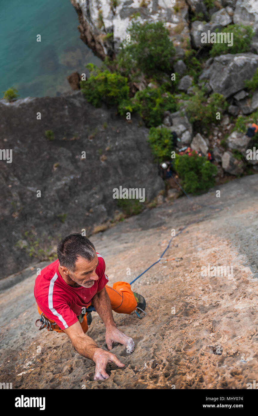 Man Klettern auf Kalkfelsen, Ansicht von oben, Ha Long Bay, Vietnam Stockfoto