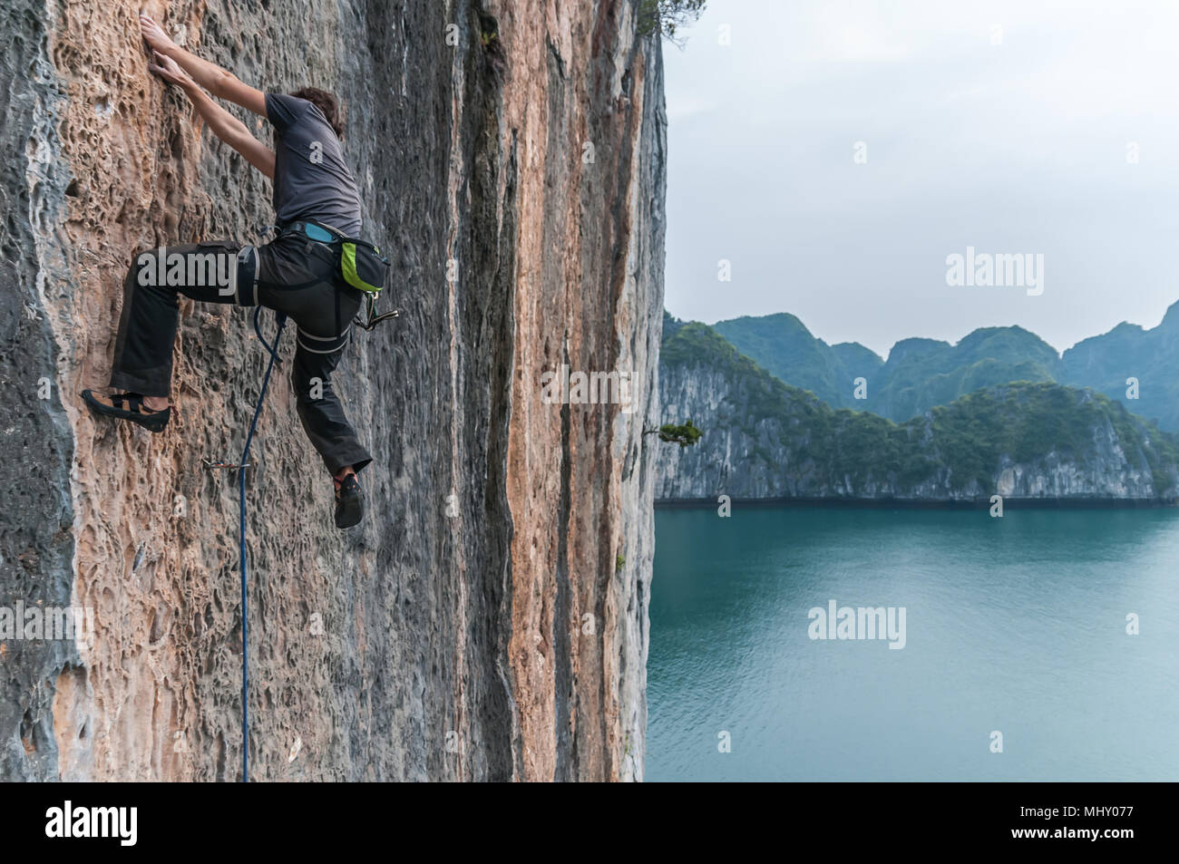 Man Klettern auf Kalkfelsen, Ha Long Bay, Vietnam Stockfoto