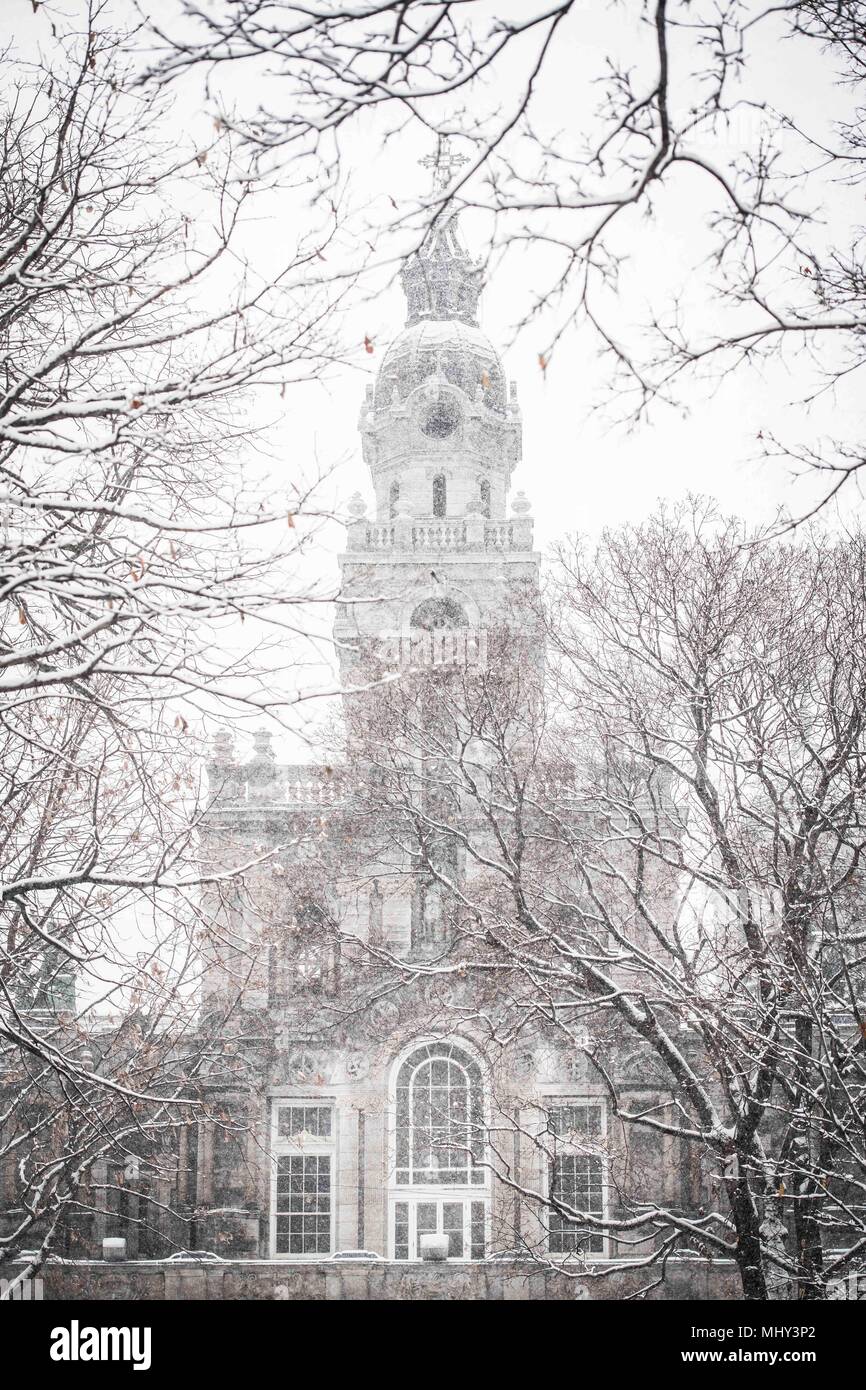 Blick durch verschneite Bäume der Eglise Saint Enfant Jesus du Mile End, St Dominique Straße, Montreal, Kanada Stockfoto