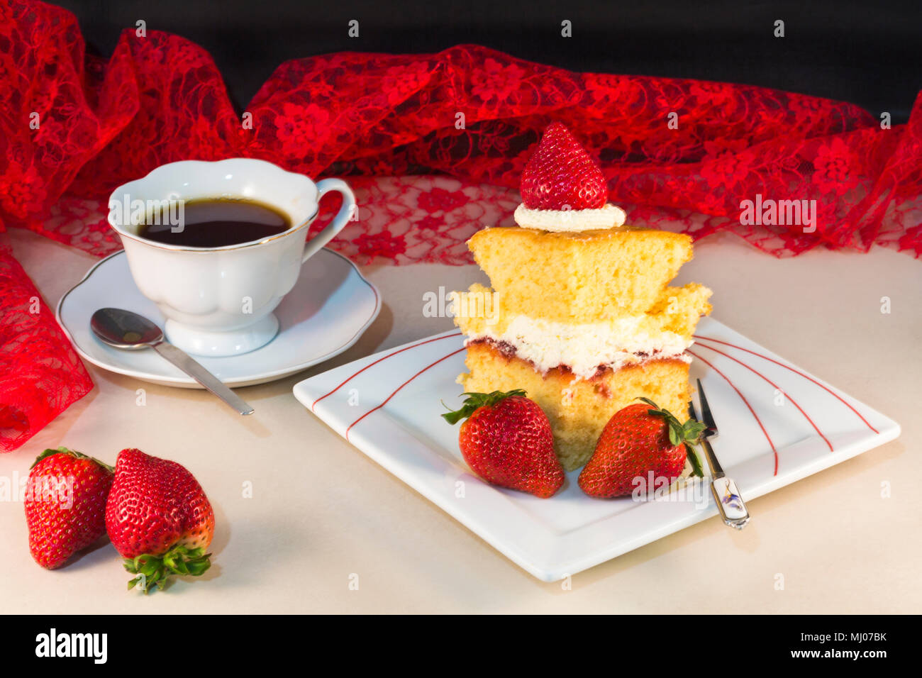Stück hausgemachten Kuchen mit Erdbeeren und Sahne auf Platte mit Tasse Tee-Konzept der Sommer Stockfoto