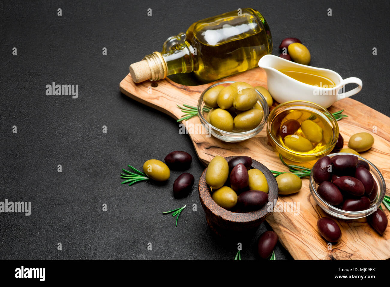 Schwarze und Grüne Oliven und Öl auf Holz Schneidebrett Stockfoto