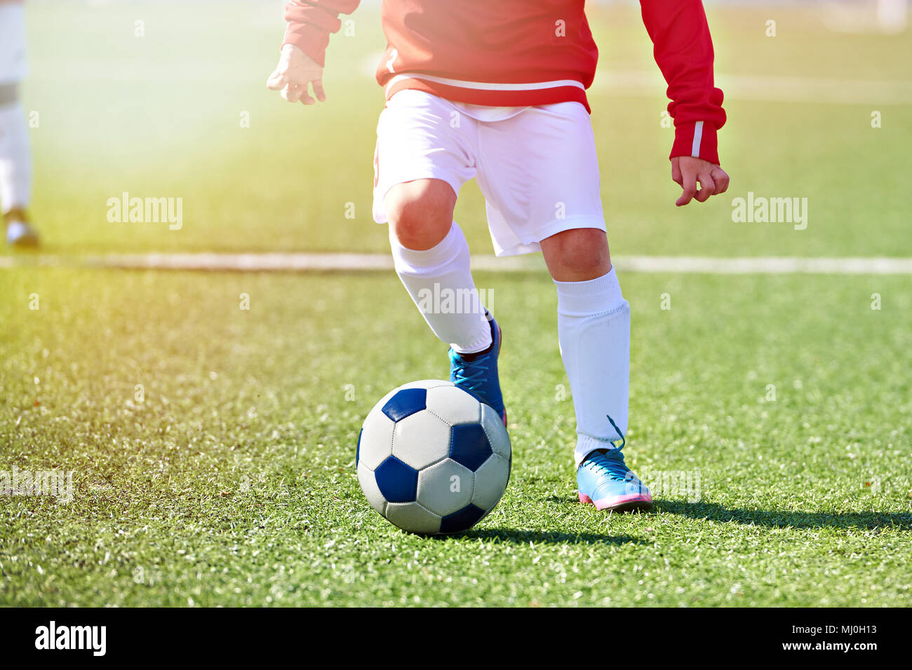 Fuß eines Kindes fußball Spieler und den Ball auf dem Fußballplatz Stockfoto