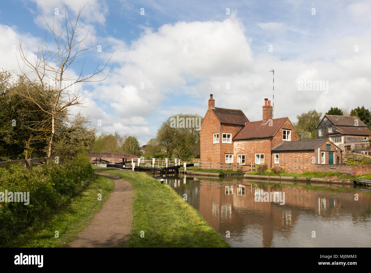 Die lock keepers Cottage, neben einem Schloss auf dem Grand Canal, spiegelt sich im Wasser. Stockfoto