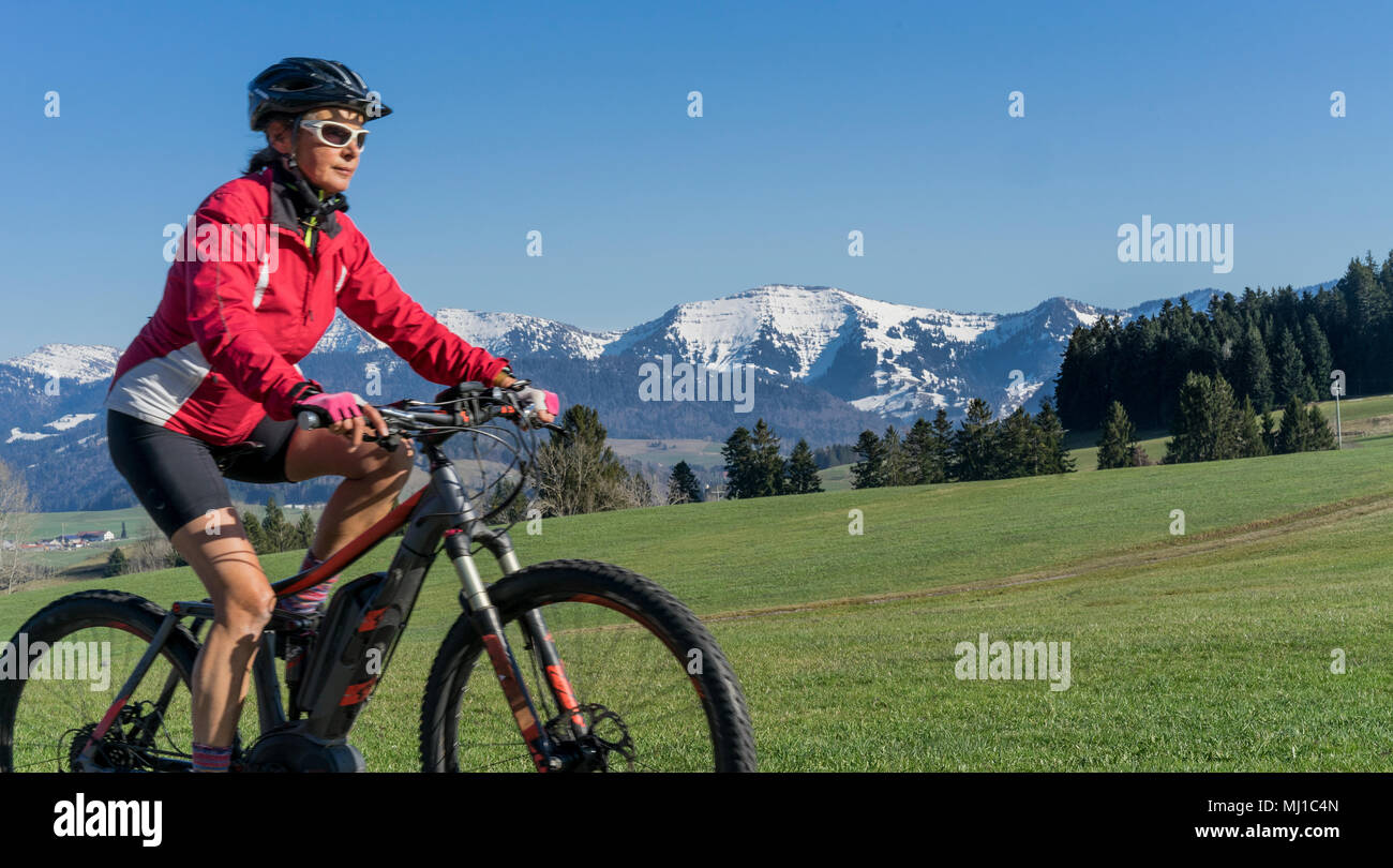 Ältere Frau Mountainbiking im Frühling im Allgäu, Deutsche Alpes Stockfoto