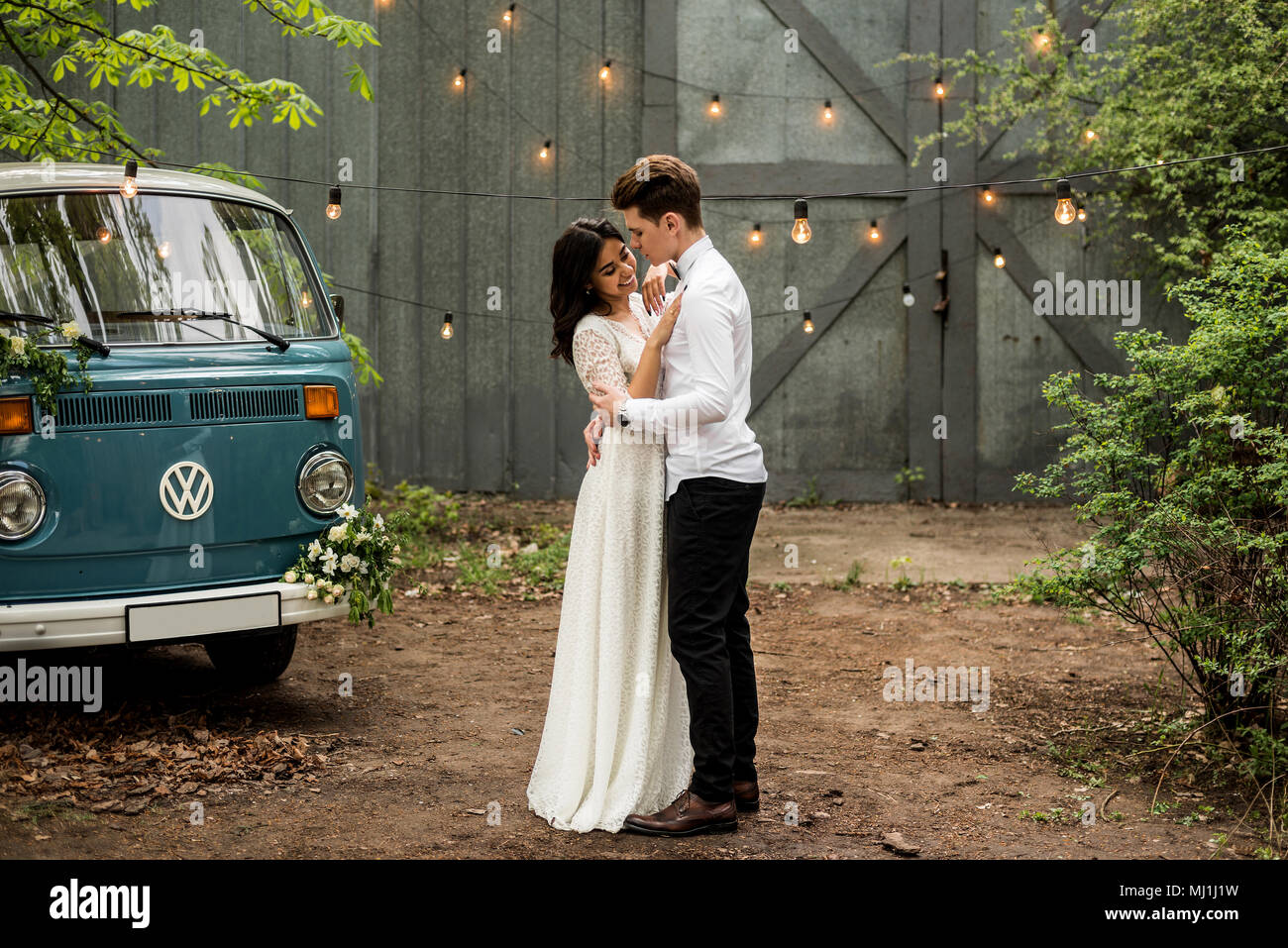 Frohes glückliches junges Paar umarmen in der Nähe von Retro minivan. Close-up Stockfoto