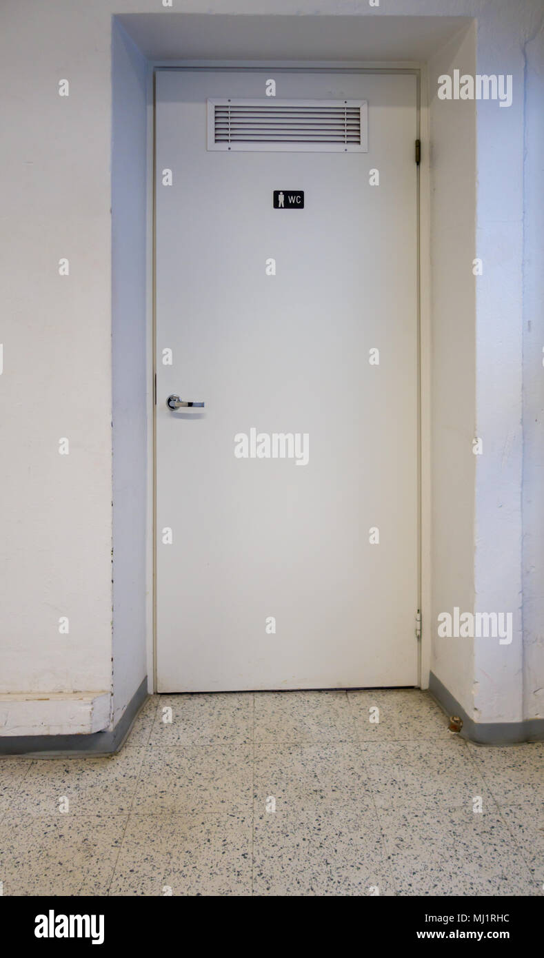 Tür der Herrentoilette in einem alten Gebäude mit weiß gestrichenen Wänden Stockfoto