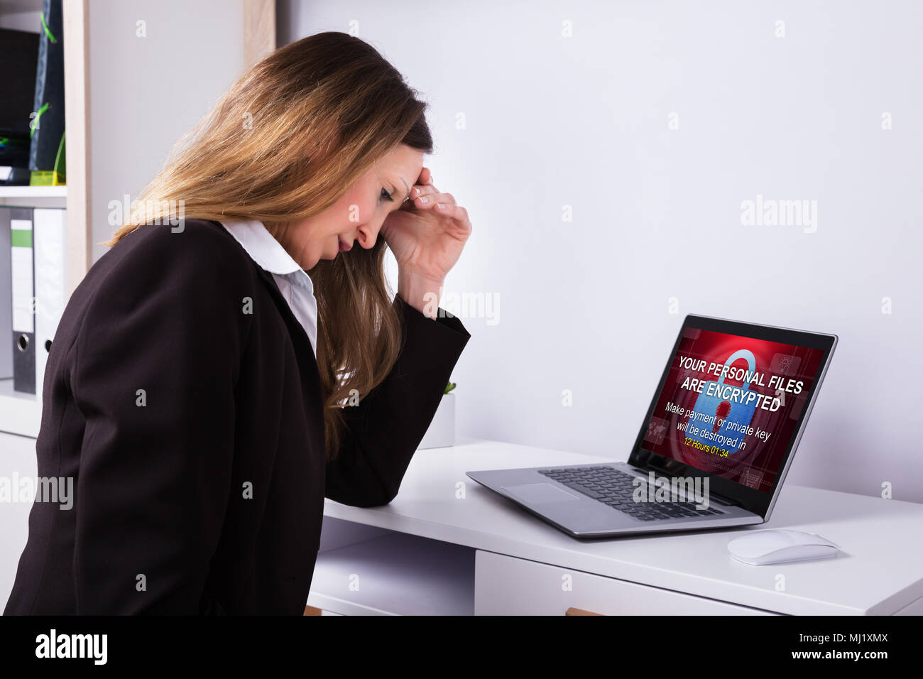 Verärgert Geschäftsfrau im Büro mit Laptop Bildschirm mit persönlichen Dateien verschlüsselt Text Stockfoto