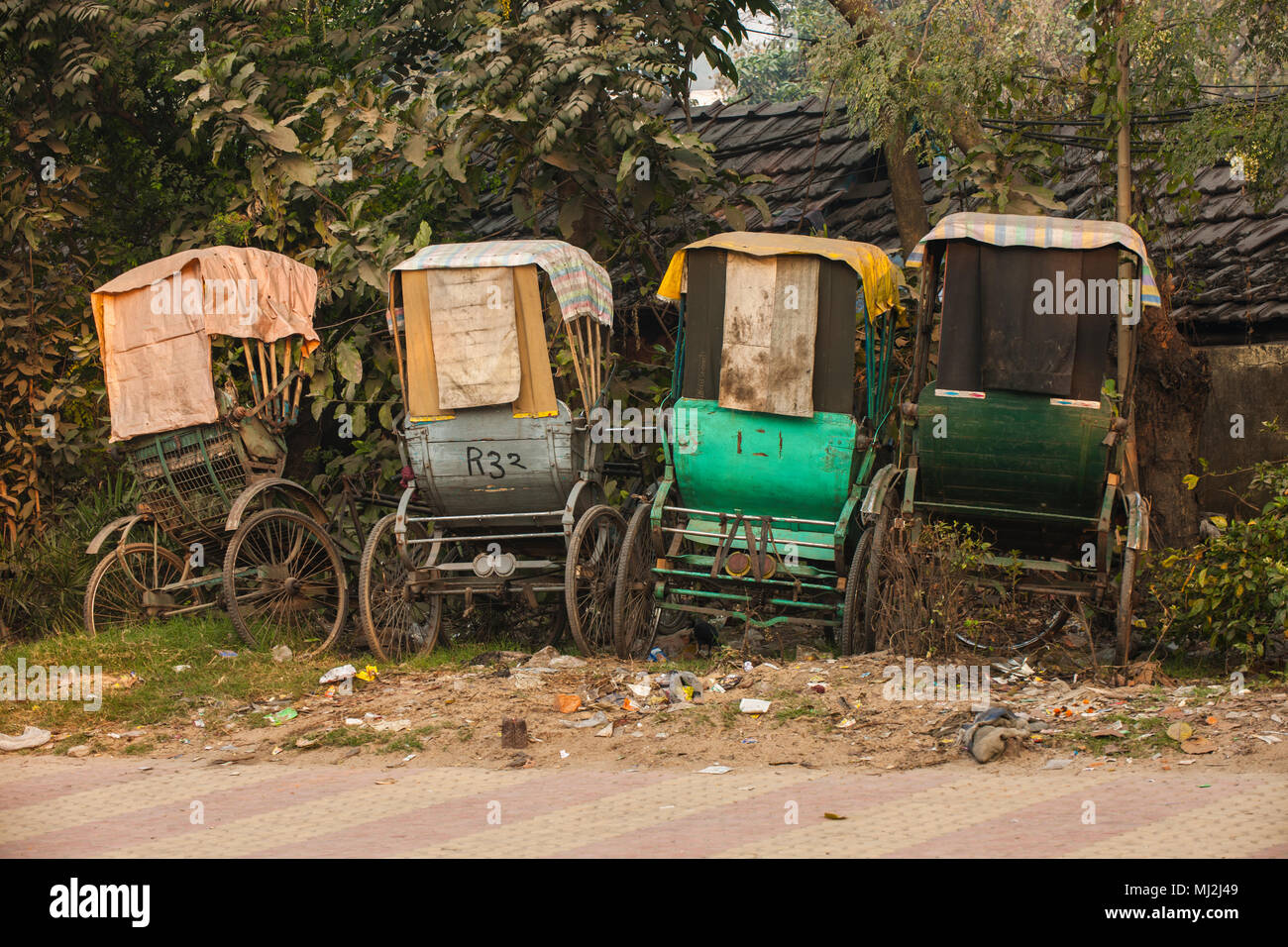 Vier rikschas und ein Fahrrad auf der Seite einer Straße geparkt in Kalkutta, Indien Stockfoto