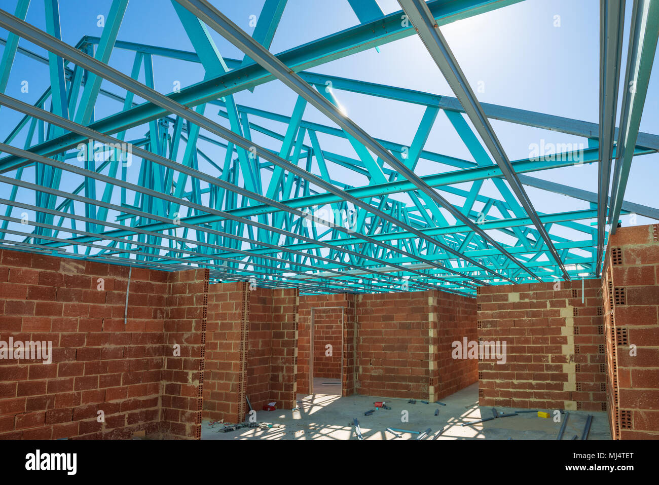 Neuen Wohngebiet brick House Konstruktion mit Dach metal Framing gegen einen blauen sonnigen Himmel. Baustelle innere Ansicht Stockfoto