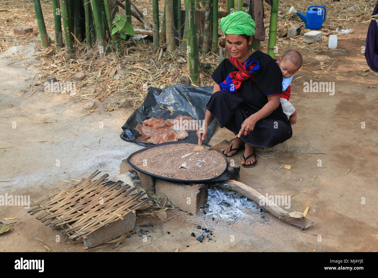Eine Frau mit einem Baby ist Kochen ein dünnes Brot in einem Bett von heißen Sand in der Nähe des Inn Dein Pagode, westlich von Inle See, Shaw Provinz, Myanmar (Birma). Stockfoto