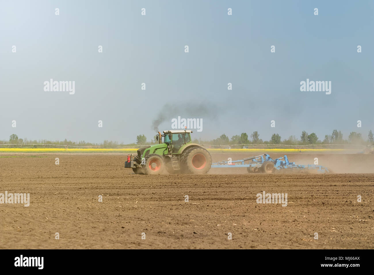 Bauer im Traktor Vorbereitung land Saatbeet Grubber. Landwirtschaft Schlepper Landschaft. Stockfoto