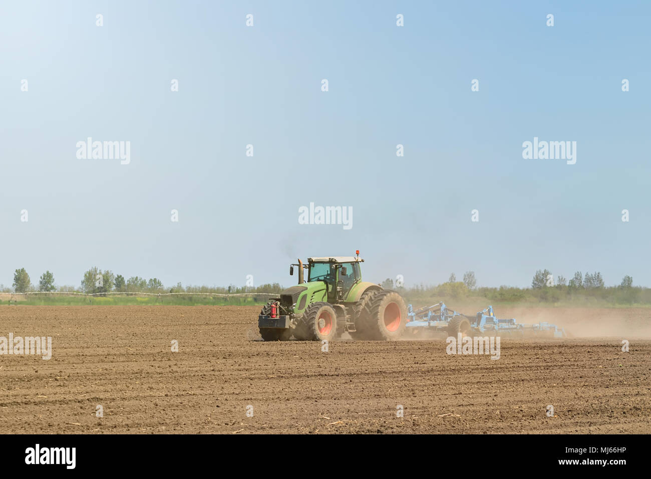 Bauer im Traktor Vorbereitung land Saatbeet Grubber. Landwirtschaft Schlepper Landschaft. Stockfoto