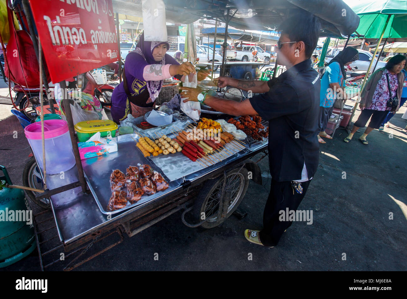 Khao Lak, Thailand - 22. Februar 2016: unbekannter Mann kaufen Frühstück von lokalen Kaufmann mit Ihrer mobilen Abschaltdruck auf Morgen Markt. Die thailändische Küche ist ren Stockfoto