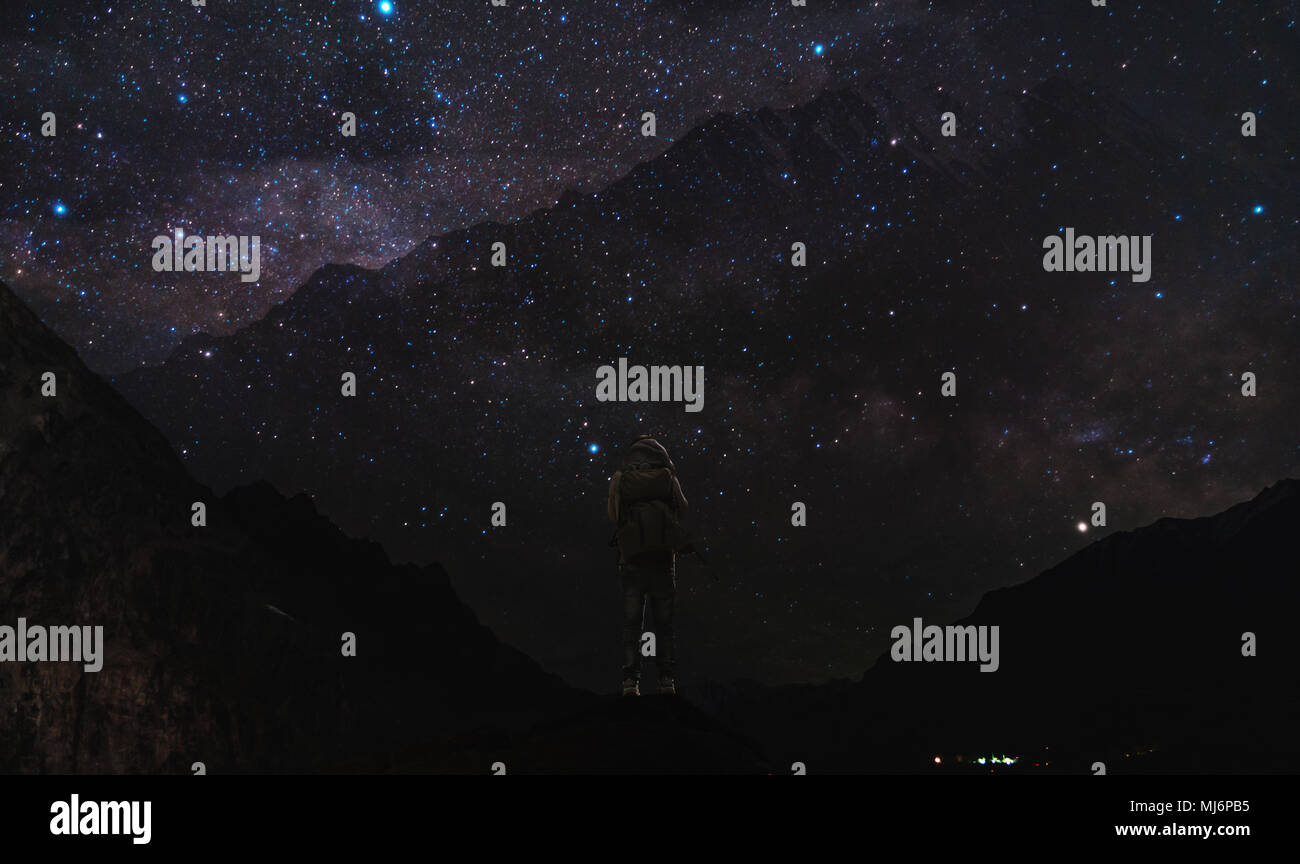 Nacht Landschaft, silhouette Berge mit klaren Himmel voller Sterne, die Milchstraße in der Nacht, und siehe, ein Mann stand auf Berggipfel und Nachthimmel genießen. Stockfoto