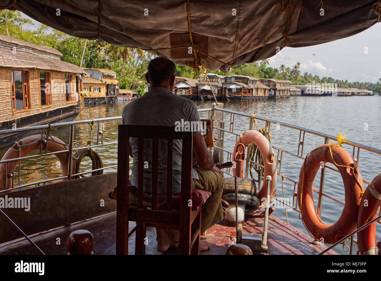 Alappuzha, Kerala/Indien - 15. April 2018: ein Kapitän ist die Lenkung ein Haus Boot durch die Wasserstraßen von Alappuzah. Stockfoto