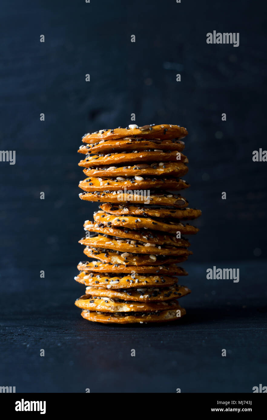 Cracker mit Mix Samen über dunklen schwarzen Holztisch Stockfoto