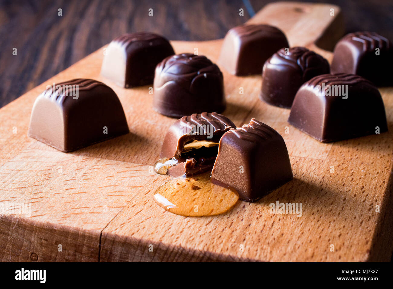 Alkohol fließt aus der Schokolade auf Holz- Oberfläche. Dessert Konzept. Stockfoto