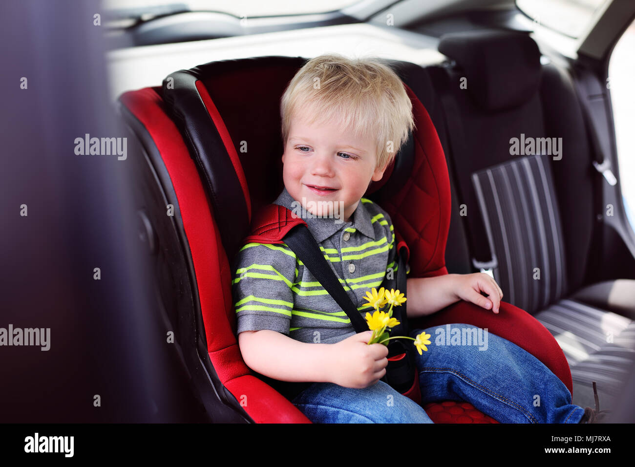 Porträt eines jungen Kindes von einem Jungen mit blonden Haaren in einem kinder Autositz. Stockfoto