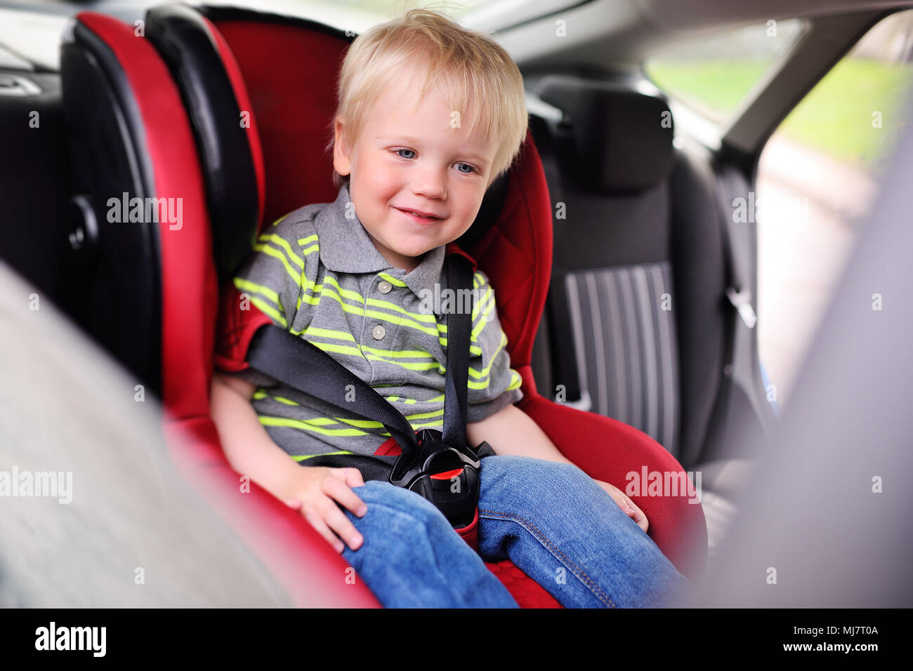 Porträt eines jungen Kindes von einem Jungen mit blonden Haaren in einem kinder Autositz. Stockfoto