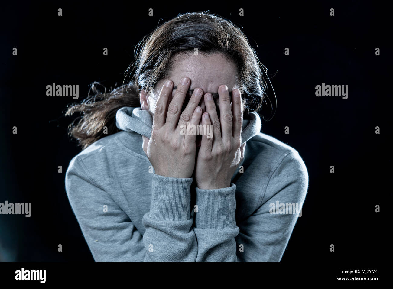 Konzept der Angst, Scham, Gewalt und Depression. Attraktive latin depressiven Frau, die ihr Gesicht mit den Händen auf einem isolierten schwarzen Hintergrund Stockfoto