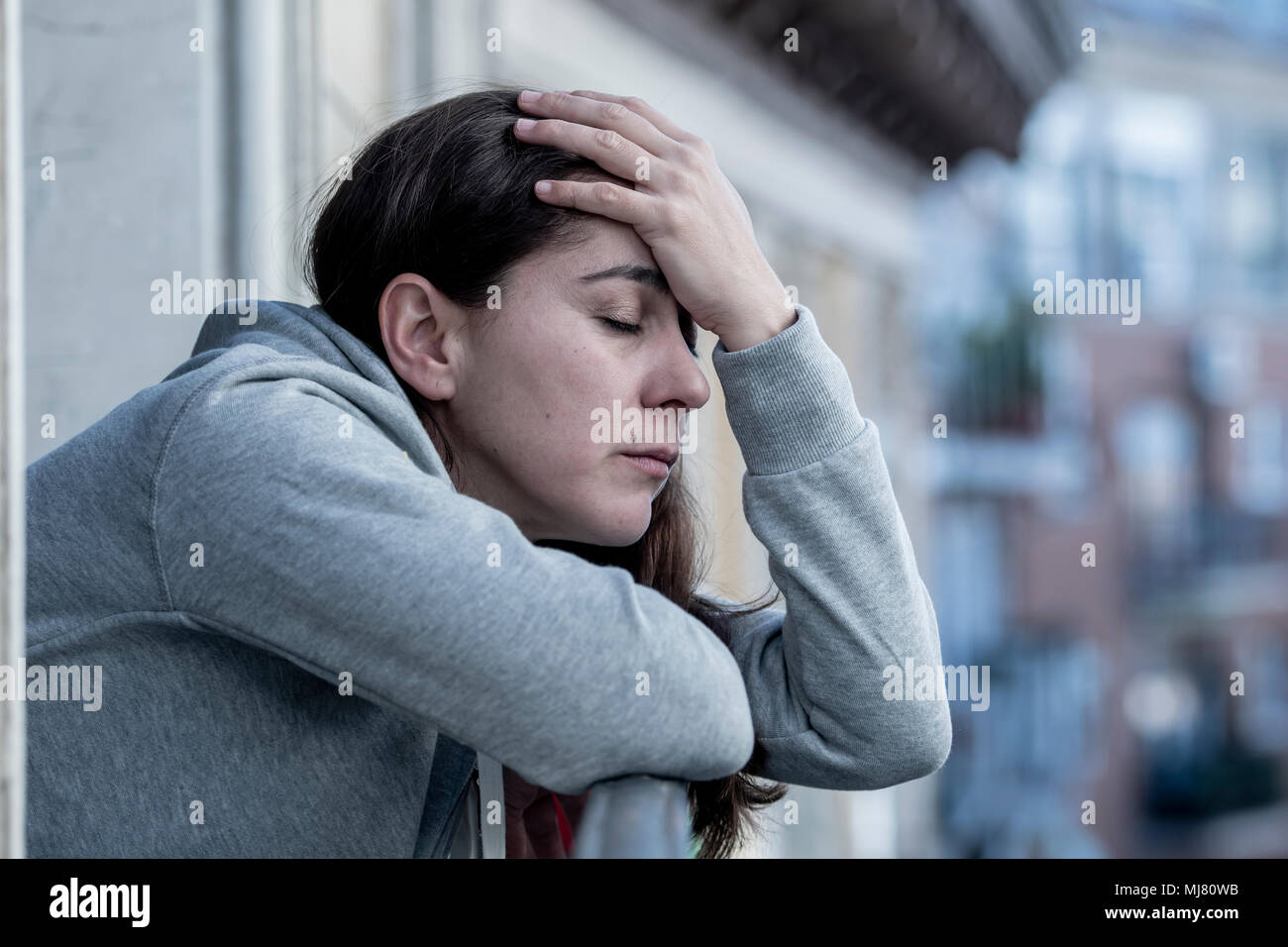 Junge Latein. traurig und deprimiert Frau, die auf einem Balkon Gefühl überwältigt und Leiden Depressionen in der psychischen Gesundheit Konzept Stockfoto