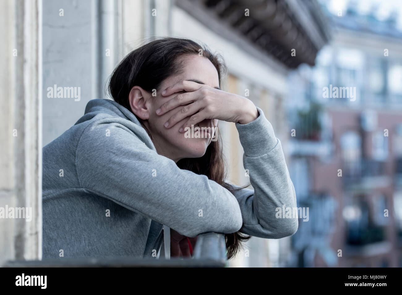 Junge Latein. traurig und deprimiert Frau, die auf einem Balkon Gefühl überwältigt und Leiden Depressionen in der psychischen Gesundheit Konzept Stockfoto