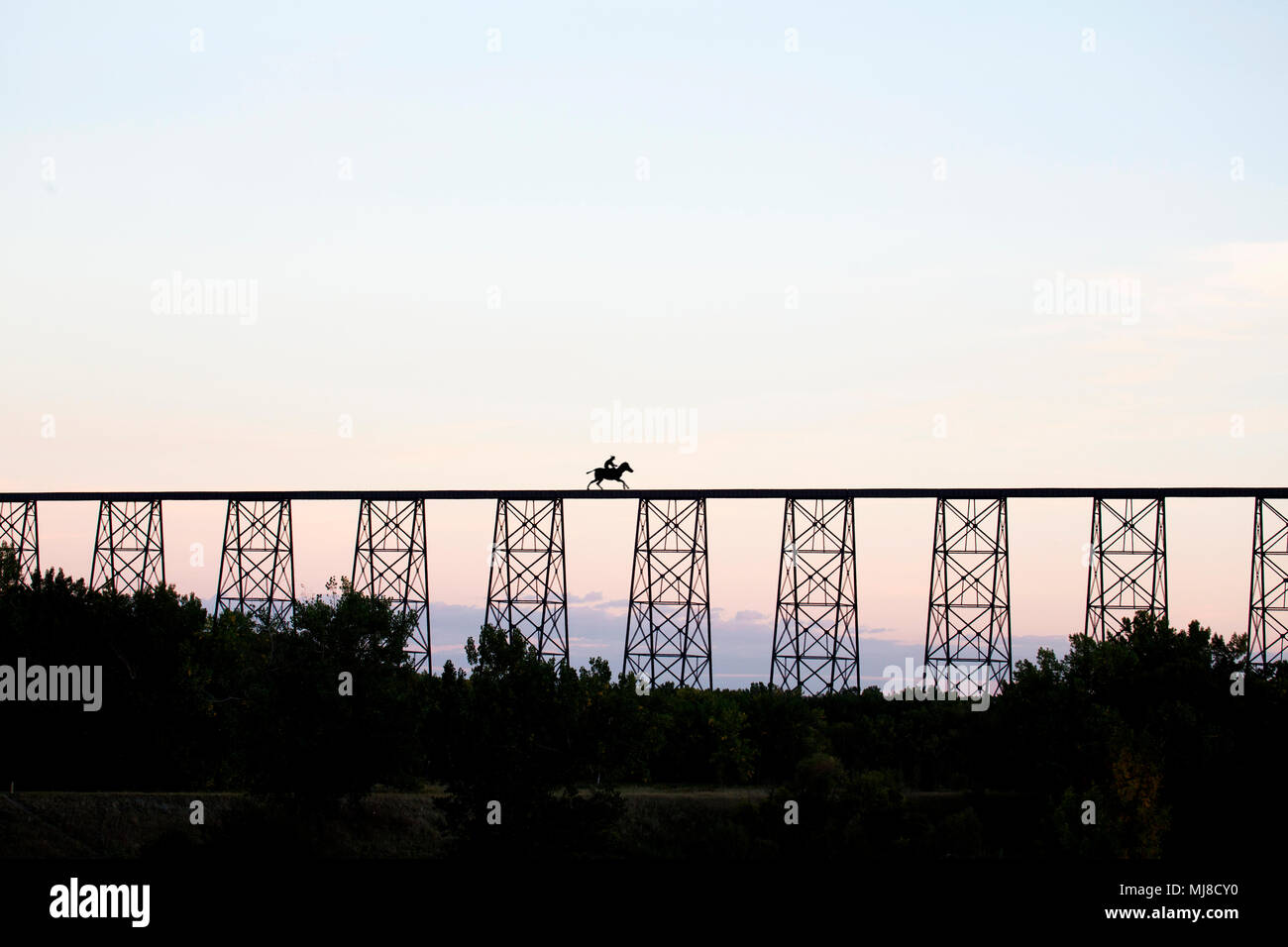 Fernsicht auf Person reiten über Bridge bei Sonnenuntergang. Stockfoto