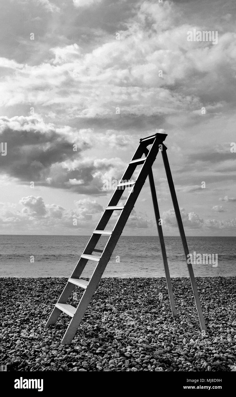 Leiter stehend auf Pebble Beach am Meer, bewölkten Himmel. Stockfoto