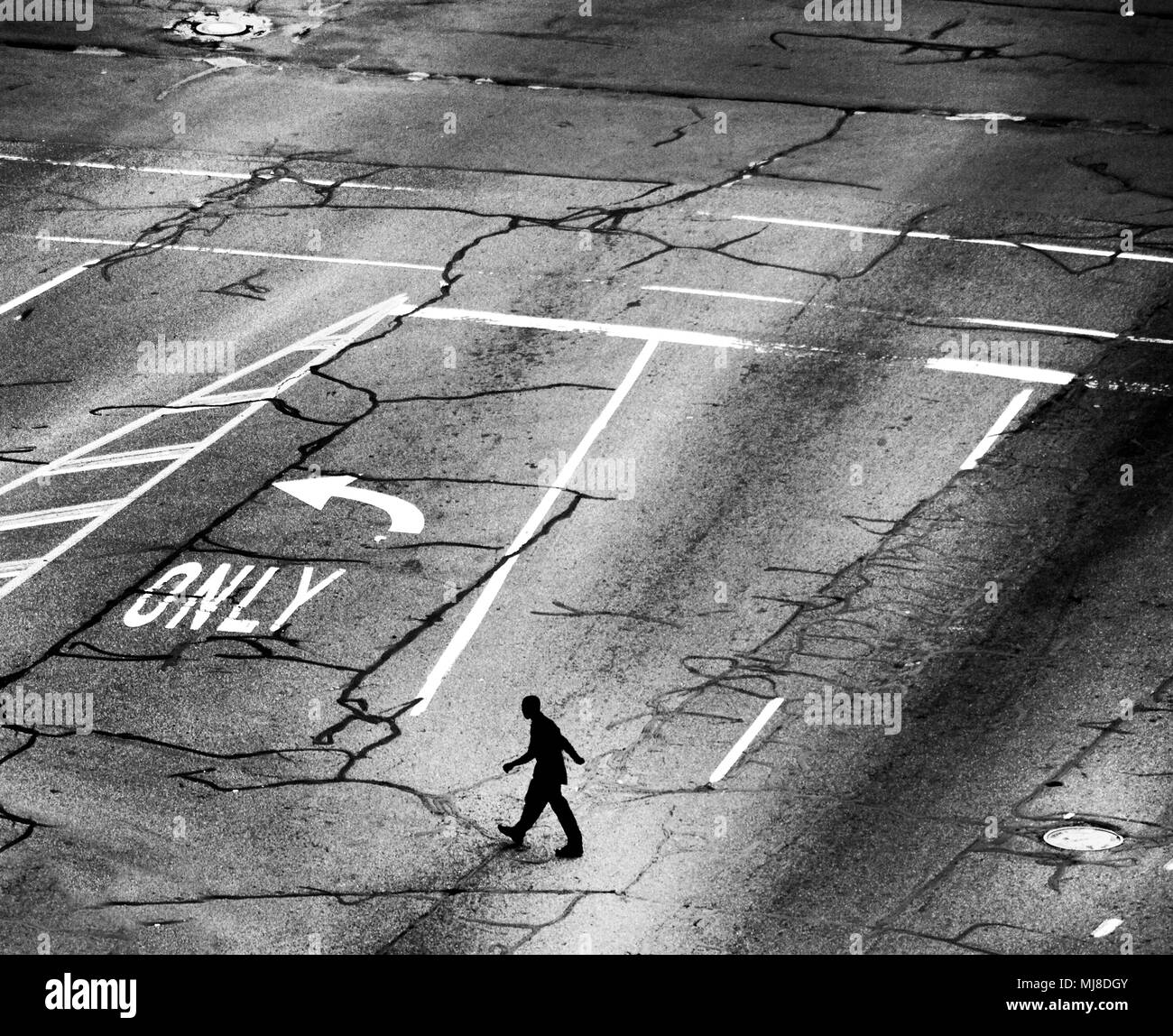 Hohe Betrachtungswinkel der Menschen auf dem Weg über eine Straße Kreuzung mit mehreren Fahrspuren, Risse im Asphalt. Stockfoto