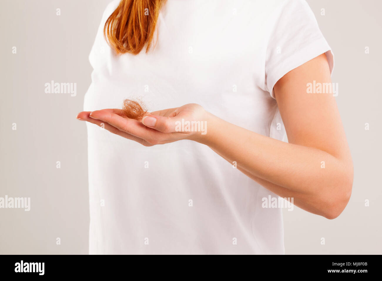 Frauen, die sich in Verlust Haar in der Hand auf grauem Hintergrund. Stockfoto