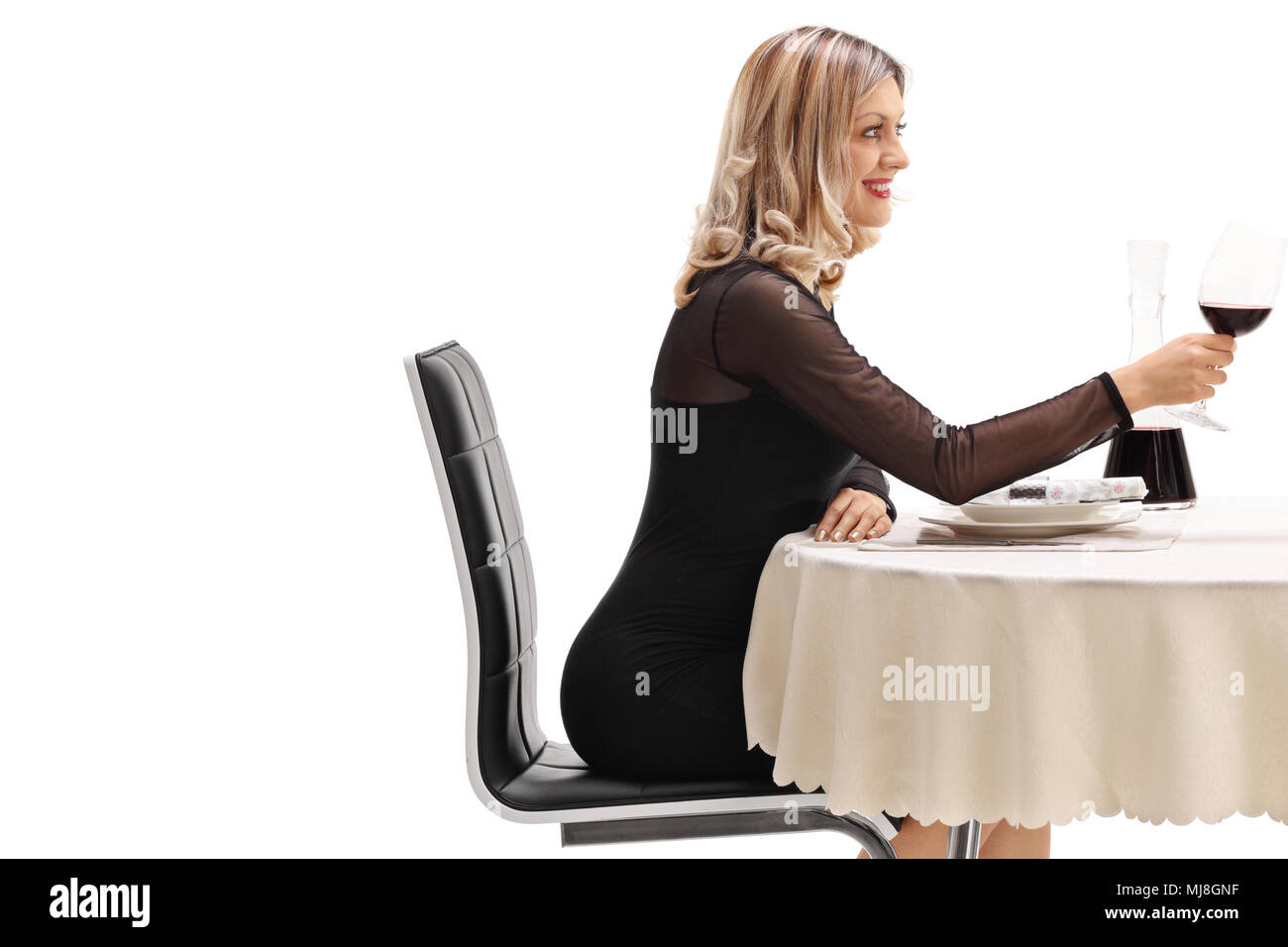 Junge Frau an einem Tisch im Restaurant mit einem Glas Rotwein auf weißem Hintergrund sitzt Stockfoto