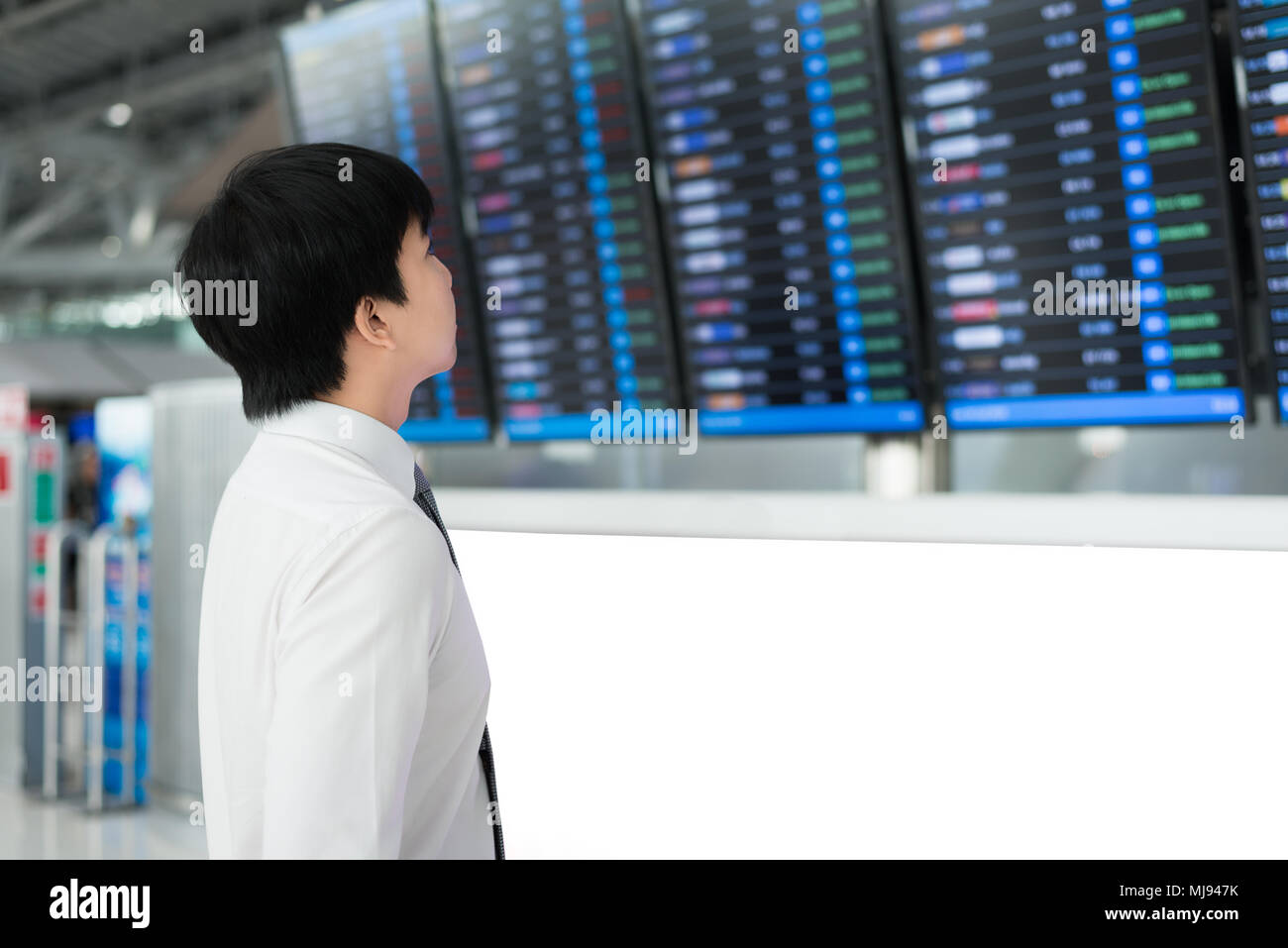 Asiatische junge Geschäftsmann mit Gepäck reisen in nahe liegenden Flugplan Flughafen warten. Business Travel-Konzept Stockfoto
