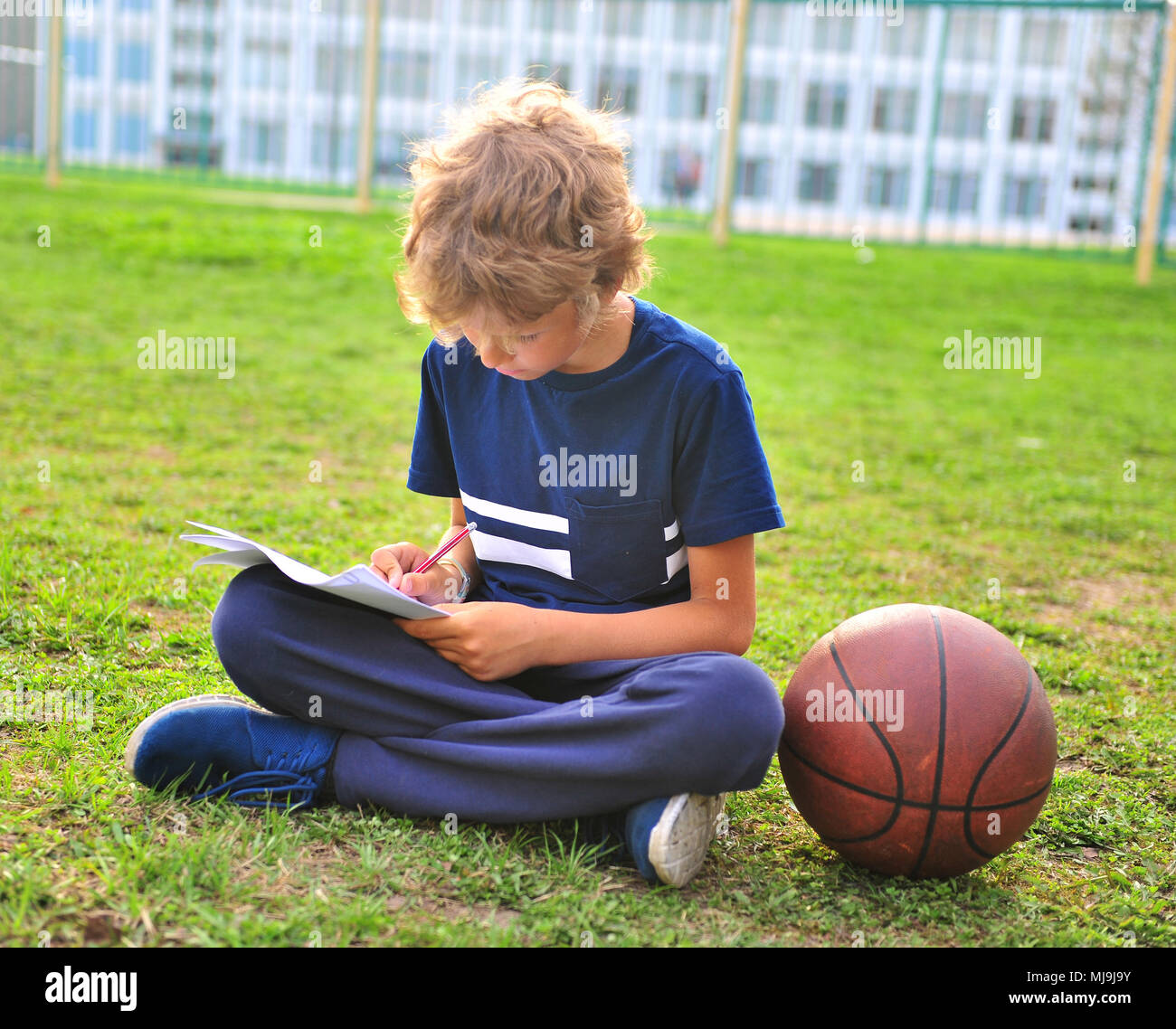Junge mit Papier und Basketball auf dem Gras Stockfoto