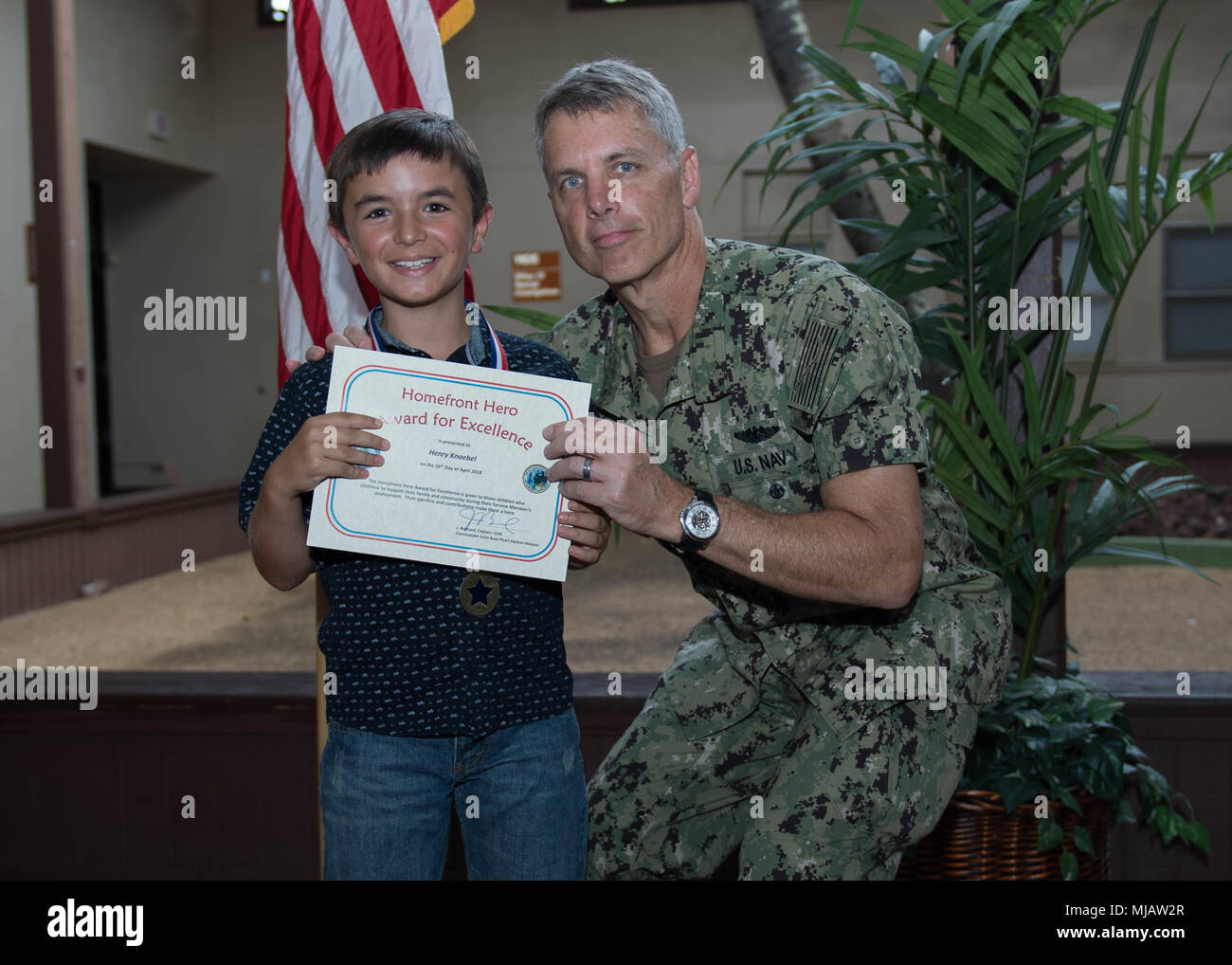 180426-N-ND 356-0054 Pearl Harbor (Apr. 26, 2018) - ein Homefront Hero Award Empfänger erhält eine Urkunde von Kapitän Jeff Bernard, Kommandeur der Joint Base Pearl Harbor-Hickam an einer militärischen und Family Support Center unter Joint Base Pearl Harbor-Hickam. Die Homefront Hero Award wurde in einer Unterstützung der Monat der militärischen Kind erstellt. (U.S. Marine Foto von Mass Communication Specialist 3. Klasse Jessica O. Blackwell) Stockfoto