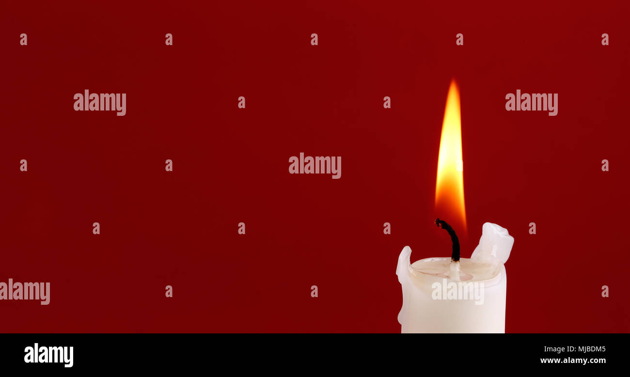 Oben eine weiße Kerze mit einer Flamme auf rotem Hintergrund mit Emty Raum. Stockfoto