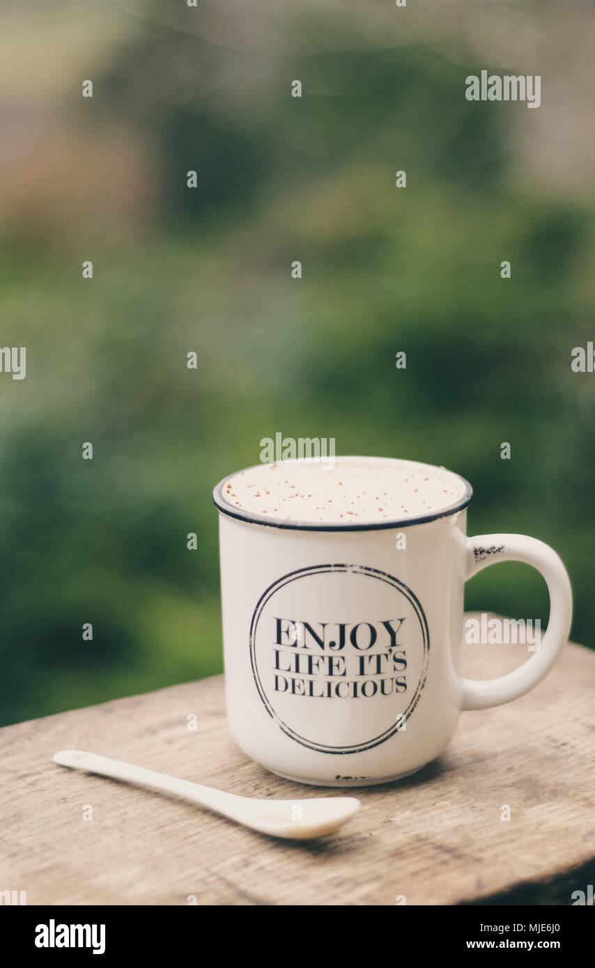 Genießen Sie das Leben - es ist köstlich: Schale mit Milchkaffee draußen auf einem Holztisch Stockfoto