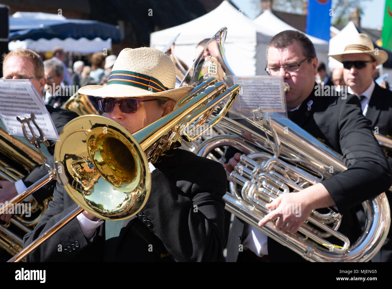 Posaunist und Tuba-Spieler in einer Blaskapelle auf der Downton Cuckoo Fair, Salisbury, Wiltshire, Großbritannien, Mai 2018. Mayday Feiertagswochenende Parade und Straßenfest bei der Ankunft des Frühlings. Stockfoto