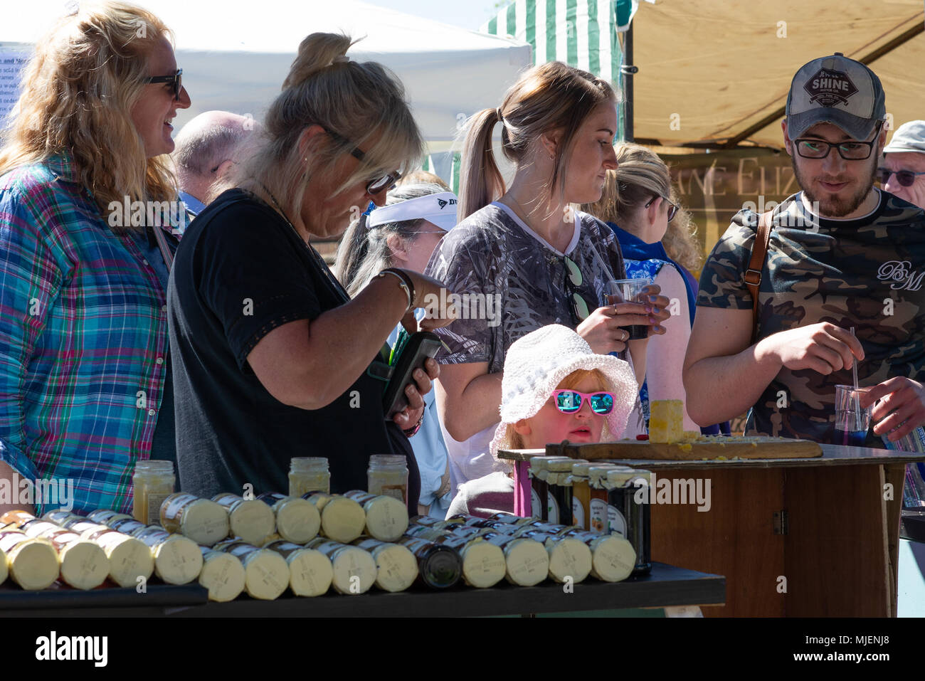 Menschen, die an einem Stand auf dem Kunsthandwerksmarkt, der Downton Cuckoo Fair, Salisbury, Wiltshire, Großbritannien, Mai 2018. Mayday Feiertag Wochenende Straßenmesse feiert die Ankunft des Frühlings. Stockfoto