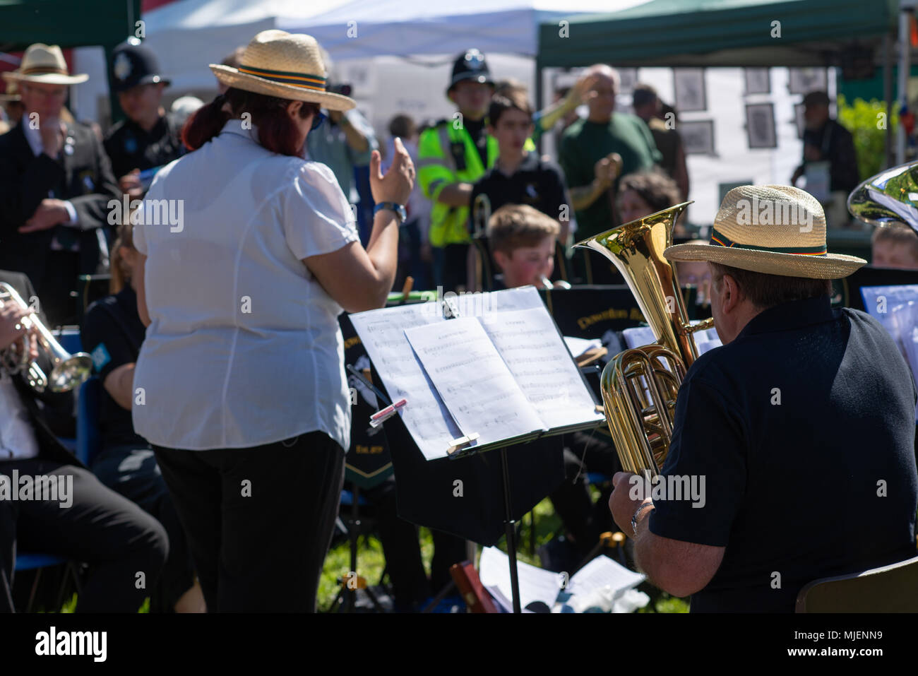 Frau, die eine Blaskapelle auf der Kuckuckmesse, Downton, Salisbury, Wiltshire, Großbritannien, dirigiert, 5. Mai 2018. Mayday Feiertagswochenende. Stockfoto