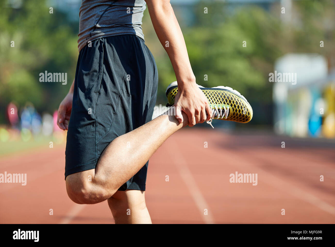 Junge asiatischer Mann-männlichen Athleten Aufwärmen stretching Beine auf Schiene. Stockfoto