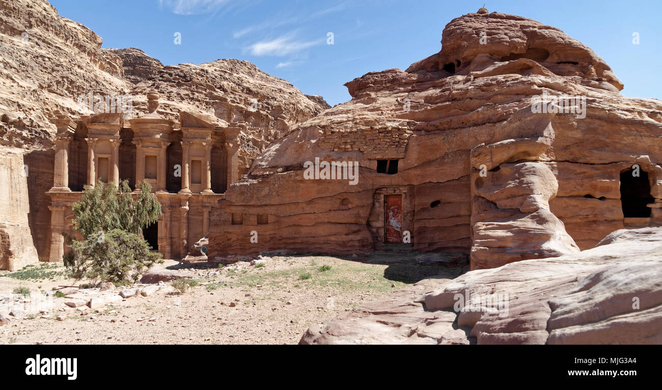 Höhlenbehausungen, die heute noch als Abstellraum und Aufenthaltsraum, mit al-deir Kloster im Hintergrund in den Bergen von Petra, Jo verwendet Stockfoto