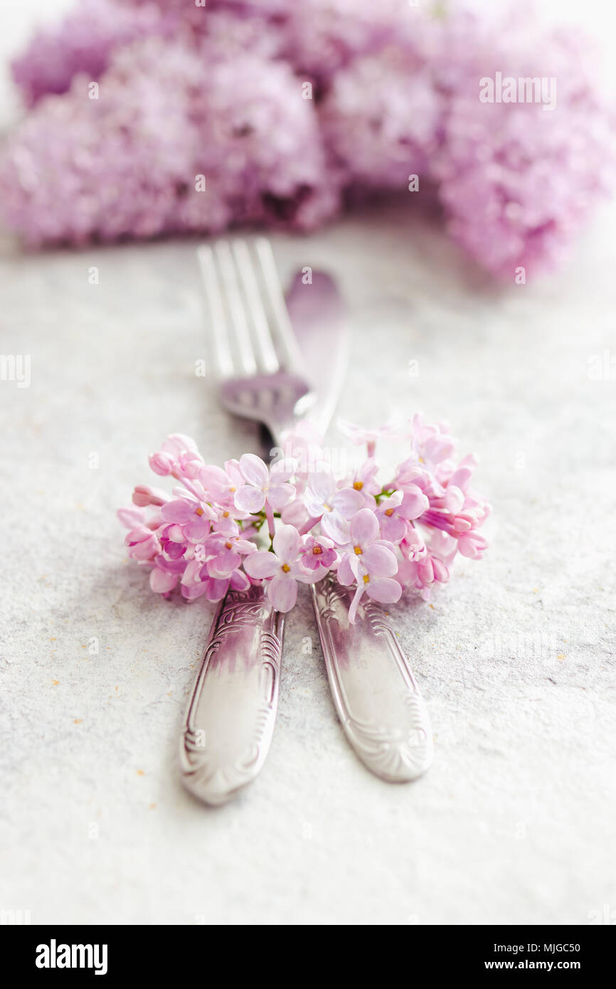Frühling Tischdekoration mit lila Blüten. Elegante Tischdekoration mit lila Blumen und vintage Besteck auf rustikalen Hintergrund. Stockfoto