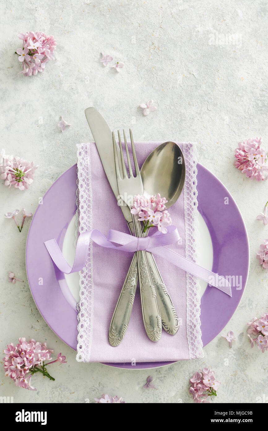 Frühling Tischdekoration mit lila Blüten. Elegante Tischdekoration mit lila Blüten, violett serviette und vintage Besteck auf rustikalen Hintergrund. Stockfoto